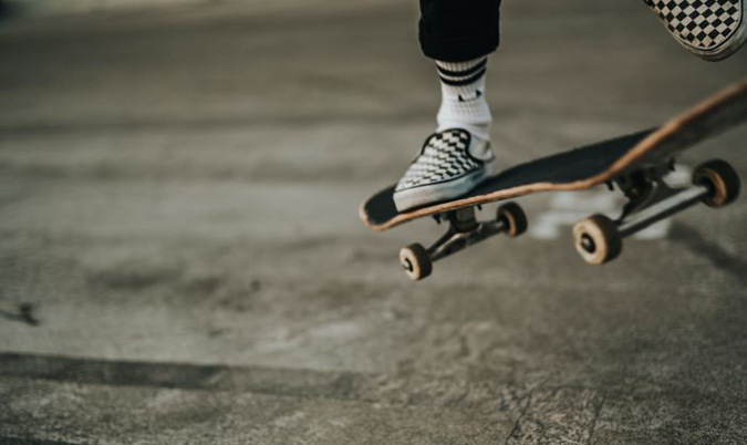 Närbild på fötter och skateboard